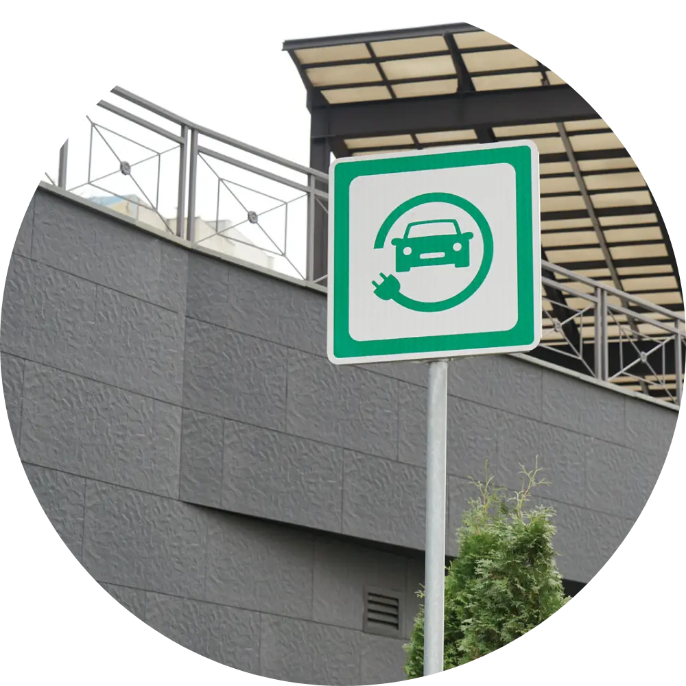 Ein Schild vor einer Tiefgarageneinfahrt, welches darauf hinweißt, das dort Elektroautos aufgeladen werden können.