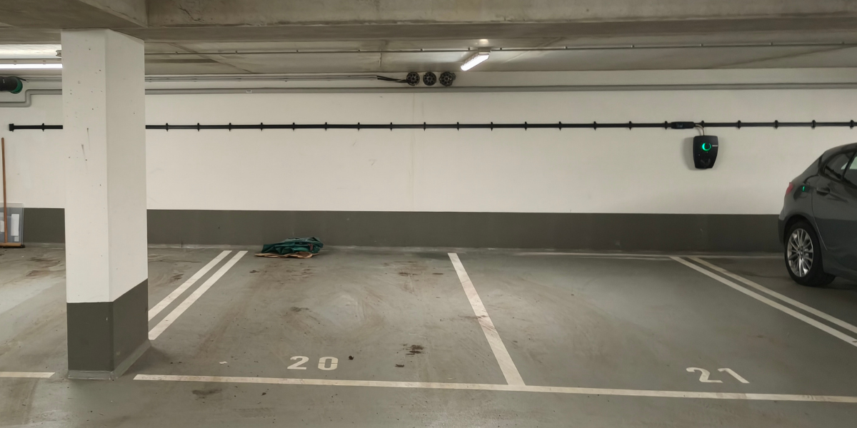 Installierte Flachleitung entlang mehrerer Stellplätze mit angeschlossener Wallbox